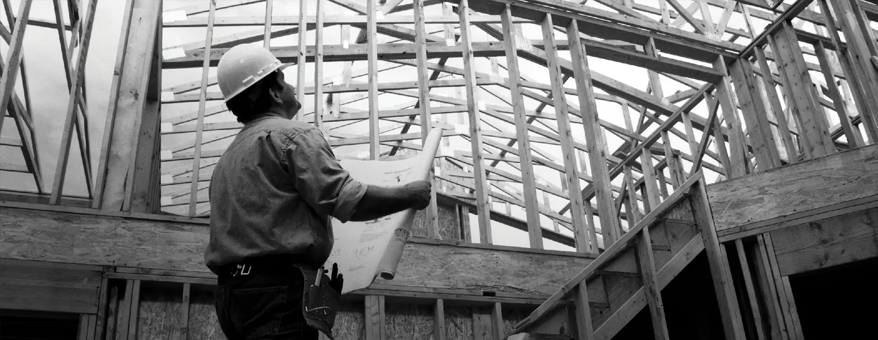 Capataz de construcción revisando planos dentro de la casa enmarcada